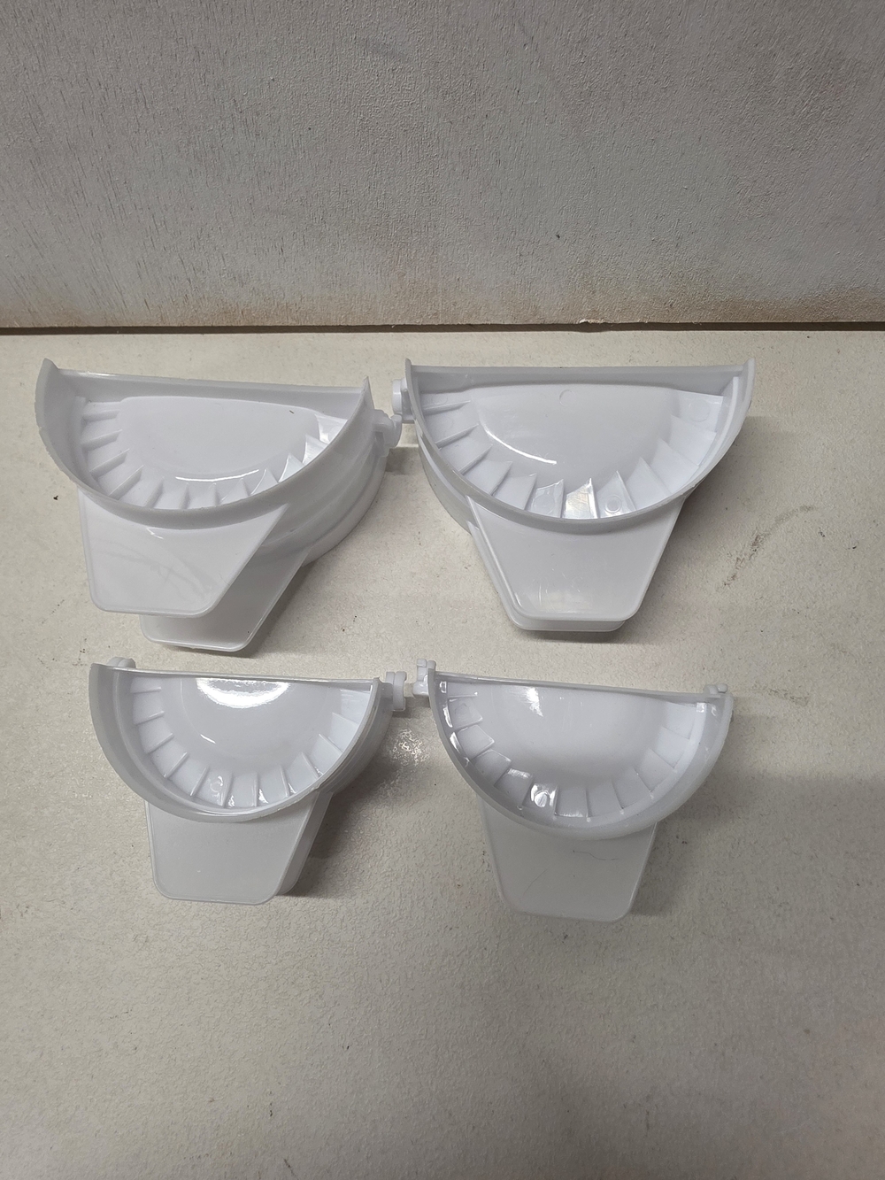 Set of 4 white plastic dumpling/empanada presses in two different sizes.
